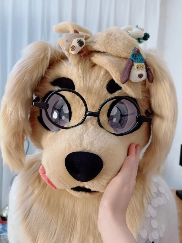 A playful black cat-like mascot with bright eyes, a purple nose, and blonde fur, wearing stylish goggles, against a teal background.